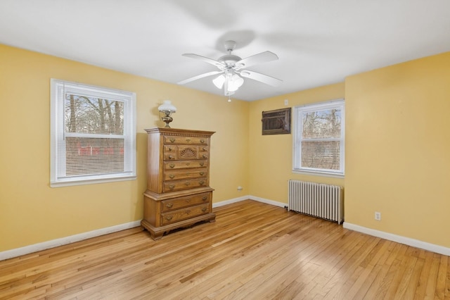 interior space featuring a wall mounted air conditioner, ceiling fan, light wood-type flooring, and radiator