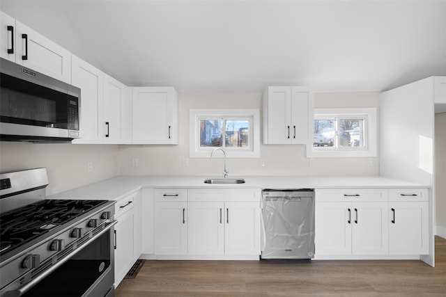 kitchen featuring white cabinetry, appliances with stainless steel finishes, light hardwood / wood-style floors, and sink