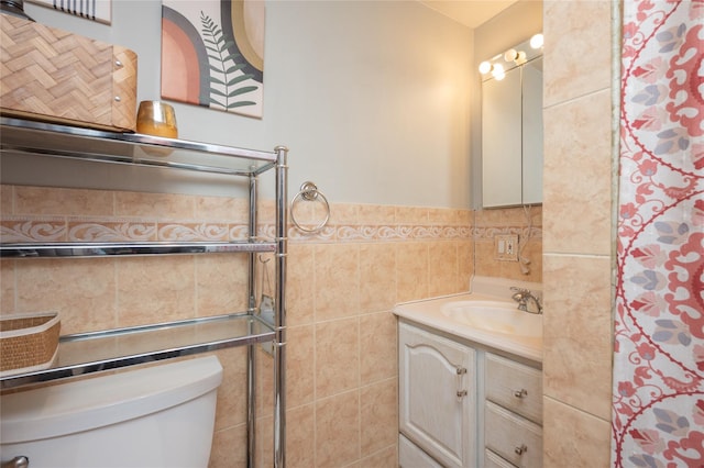 bathroom featuring vanity, toilet, and tile walls