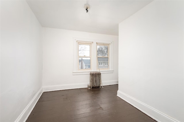 unfurnished room featuring radiator and dark hardwood / wood-style floors