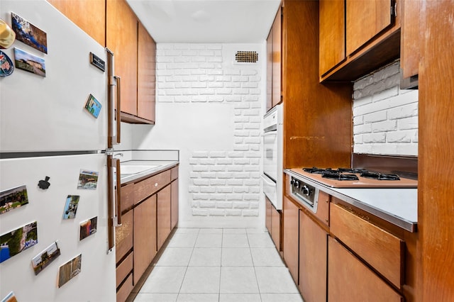 kitchen with backsplash, light tile patterned floors, and white appliances