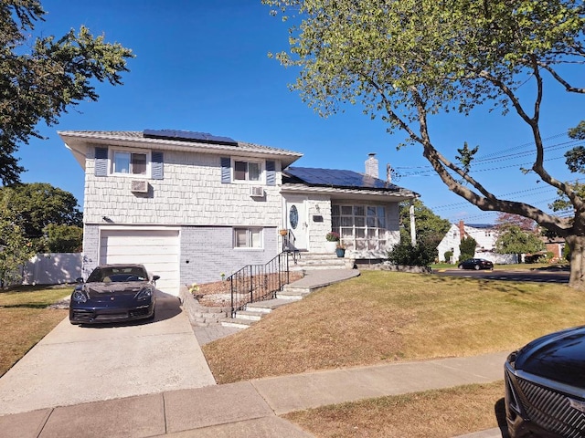 split level home with solar panels, a garage, and a front yard