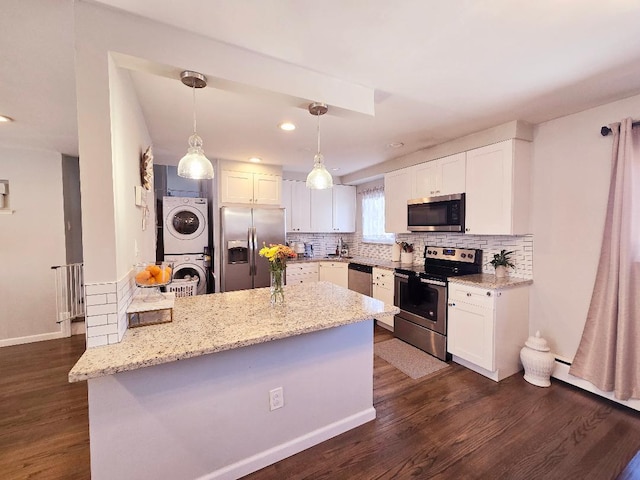 kitchen with dark hardwood / wood-style flooring, stainless steel appliances, stacked washer and clothes dryer, white cabinets, and hanging light fixtures