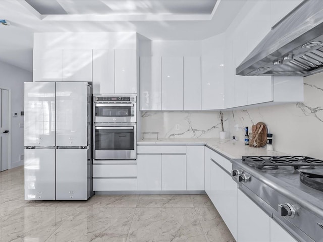 kitchen featuring white cabinetry, wall chimney range hood, and stainless steel appliances