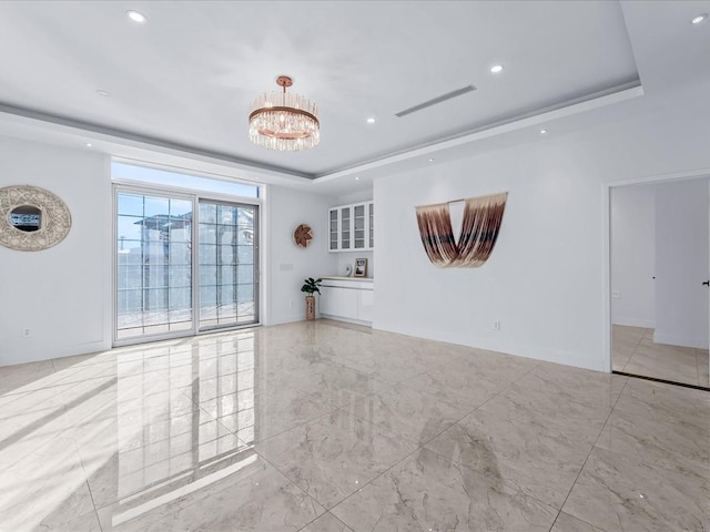 unfurnished room featuring a raised ceiling and a chandelier