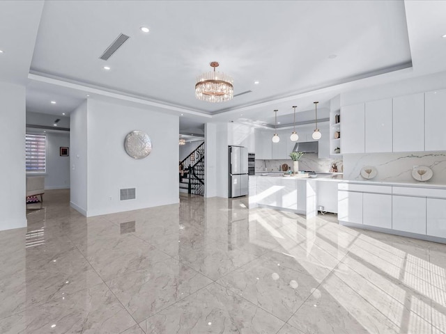 kitchen with white cabinets, stainless steel fridge, and a raised ceiling