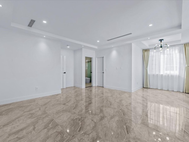 unfurnished room with a chandelier and a tray ceiling