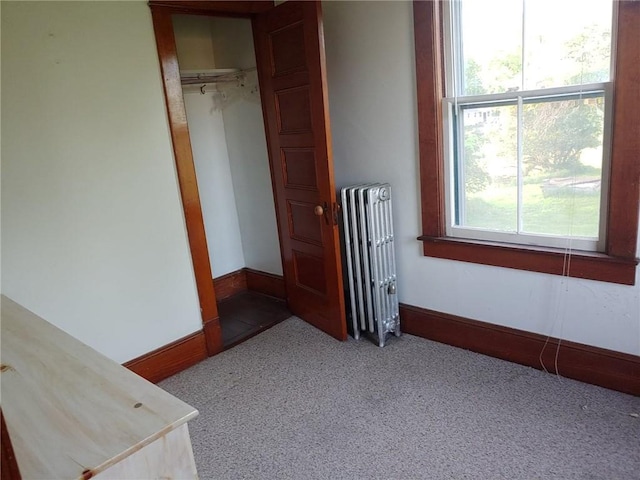 unfurnished bedroom with carpet, a closet, and radiator