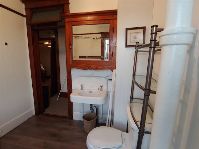 bathroom with wooden walls, sink, wood-type flooring, and toilet