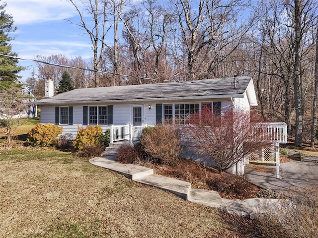 ranch-style home with a wooden deck and a front lawn