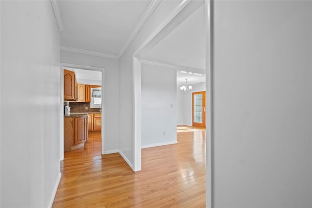 hallway featuring crown molding, a chandelier, and light wood-type flooring