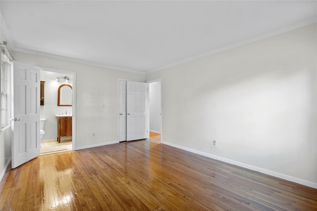 unfurnished bedroom with connected bathroom, hardwood / wood-style flooring, and ornamental molding