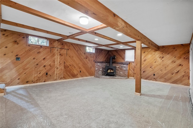 unfurnished living room with beam ceiling, a wood stove, and a wealth of natural light