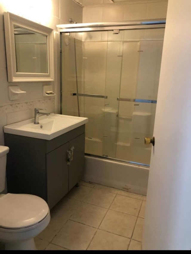 full bathroom featuring combined bath / shower with glass door, tile patterned floors, vanity, and toilet