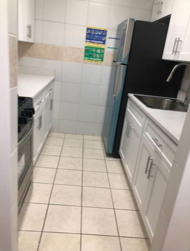 kitchen with white cabinets, sink, stove, and tile walls