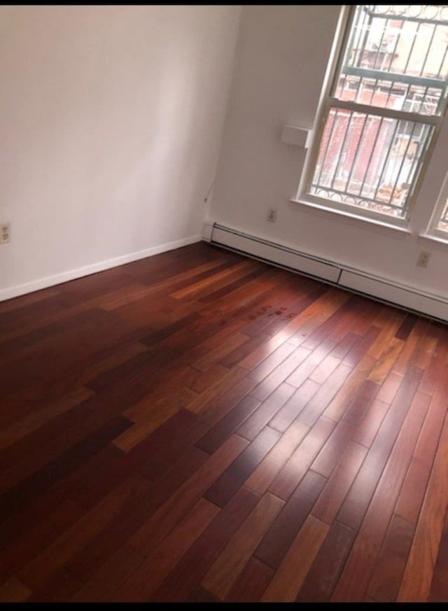 spare room with dark hardwood / wood-style flooring and a baseboard radiator