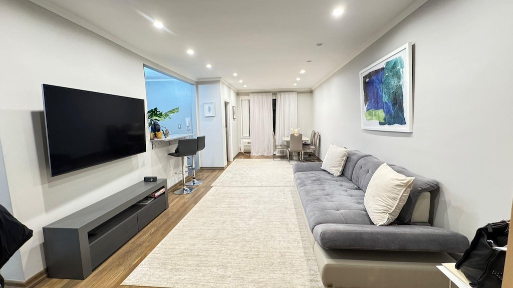 living room with light wood-type flooring and ornamental molding