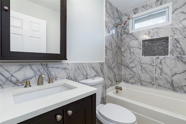 full bathroom featuring tiled shower / bath, vanity, toilet, and tile walls