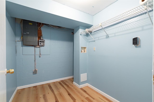 clothes washing area featuring electric panel, hardwood / wood-style floors, and washer hookup