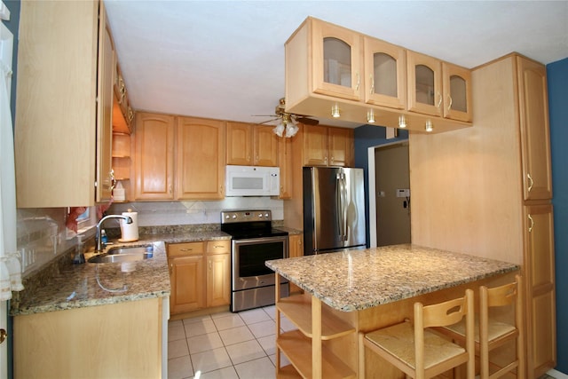 kitchen featuring decorative backsplash, light brown cabinetry, light stone counters, stainless steel appliances, and light tile patterned floors