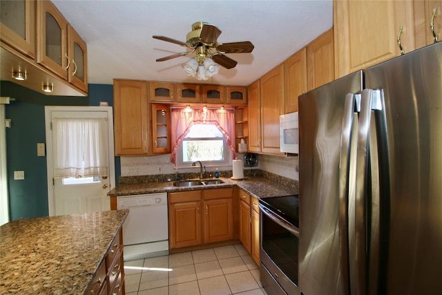 kitchen featuring sink, ceiling fan, dark stone countertops, light tile patterned floors, and stainless steel appliances