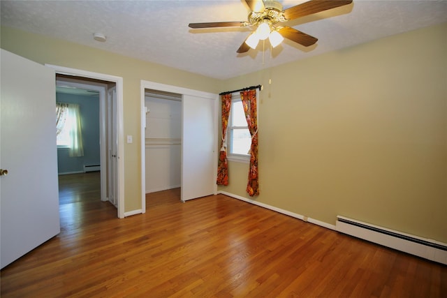 unfurnished bedroom featuring ceiling fan, baseboard heating, and multiple windows