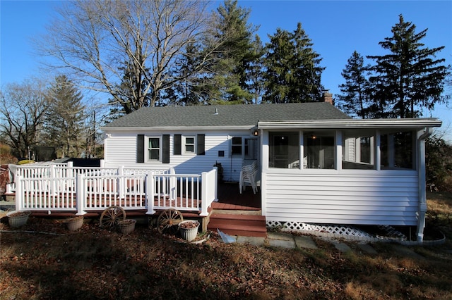 rear view of house featuring a wooden deck and a sunroom