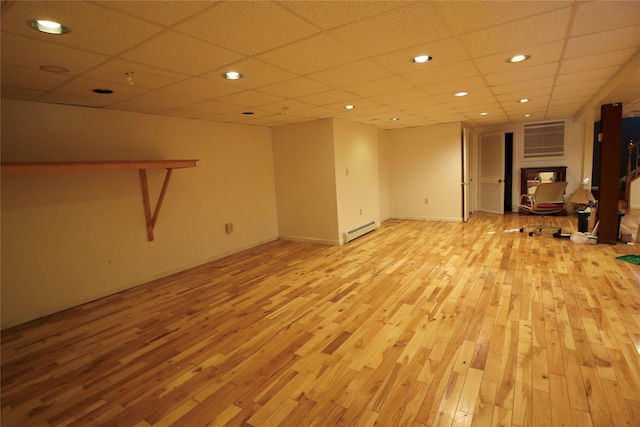 unfurnished living room with a drop ceiling, light hardwood / wood-style floors, and baseboard heating