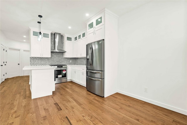 kitchen with pendant lighting, wall chimney exhaust hood, light hardwood / wood-style floors, white cabinetry, and stainless steel appliances