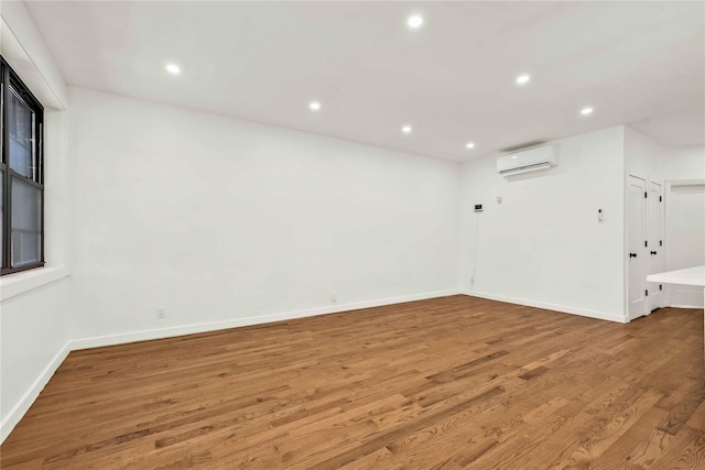 empty room with wood-type flooring and an AC wall unit