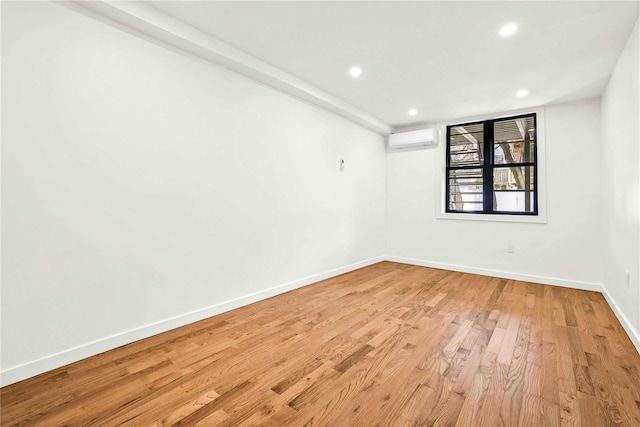 unfurnished room with light hardwood / wood-style floors and an AC wall unit