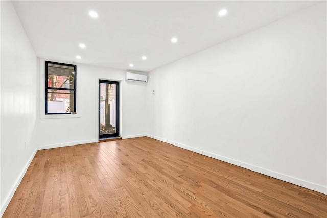 empty room featuring a wall mounted air conditioner and light wood-type flooring