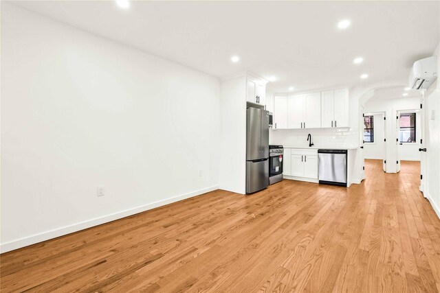 2273 E 27th St, Brooklyn, NY 11229 - kitchen with appliances with stainless steel finishes, a wall mounted AC, recessed lighting, arched walkways, and white cabinetry