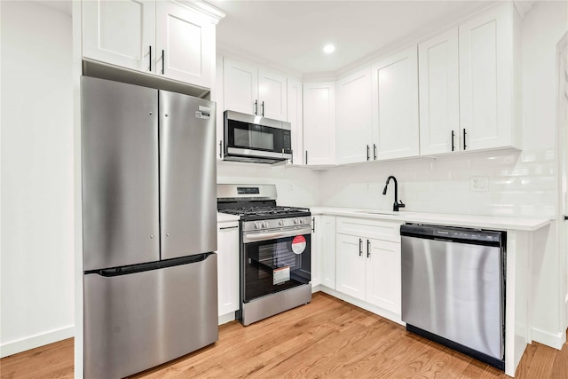 kitchen with white cabinetry, light wood-type flooring, sink, and appliances with stainless steel finishes