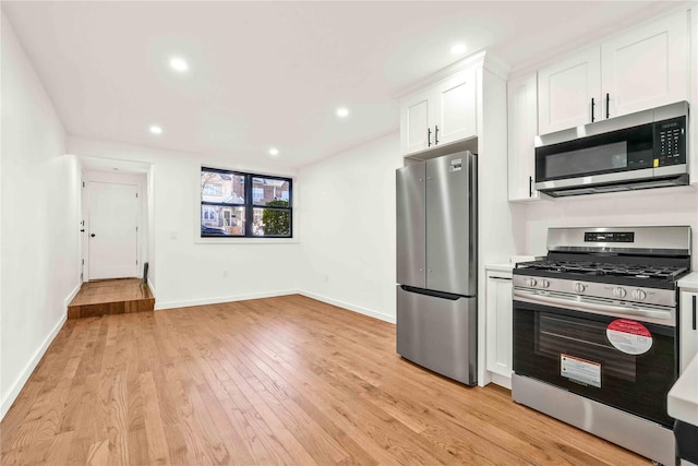 kitchen with white cabinets, stainless steel appliances, and light hardwood / wood-style flooring