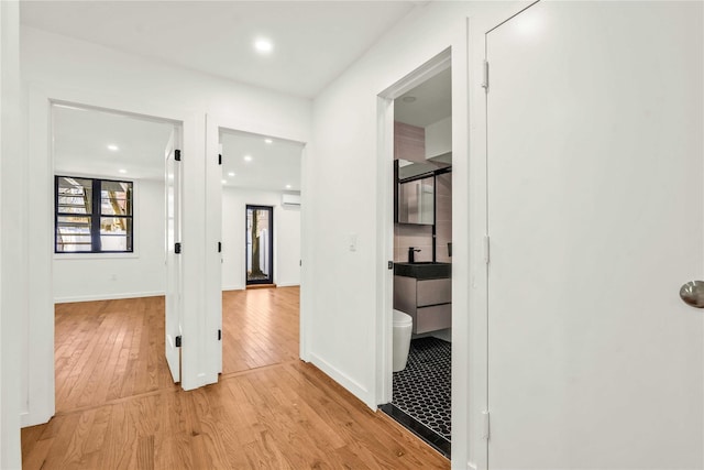 hallway featuring an AC wall unit and light wood-type flooring