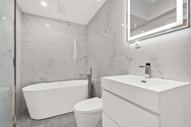 bathroom with a tub, vanity, tile walls, and toilet