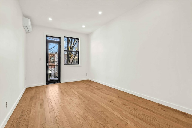 spare room featuring light wood-type flooring and a wall mounted AC