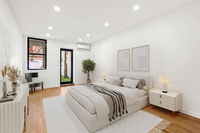 bedroom with access to outside, light hardwood / wood-style flooring, and a wall mounted AC