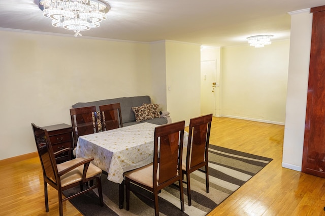 dining room with hardwood / wood-style flooring, ornamental molding, and a notable chandelier