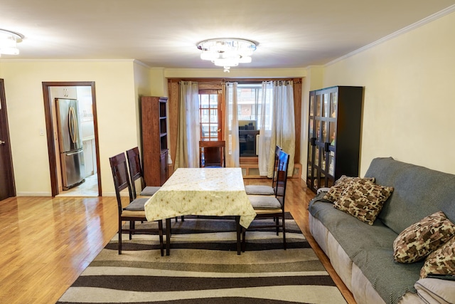 dining space with crown molding, an inviting chandelier, and light hardwood / wood-style flooring