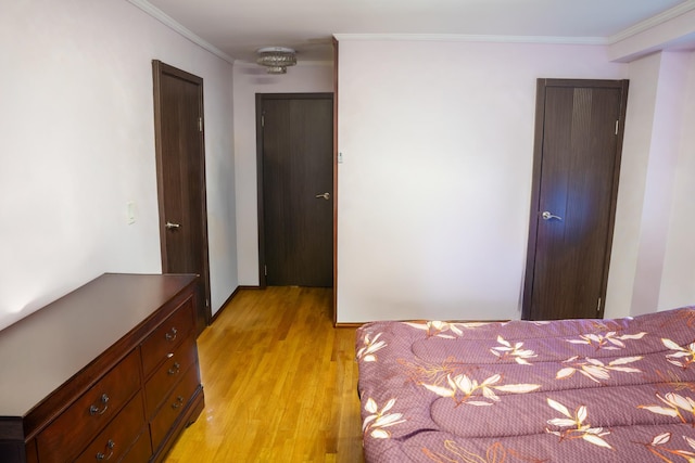 bedroom featuring light wood-type flooring, crown molding, and a closet