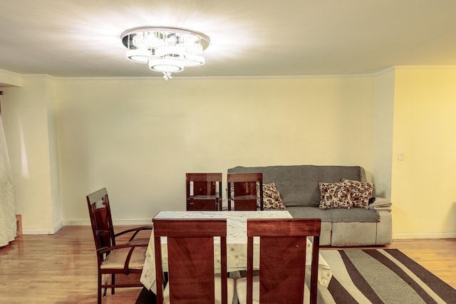 dining area featuring crown molding, light wood-type flooring, and a chandelier