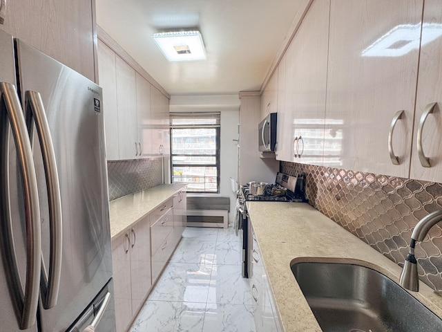 kitchen with sink, light stone counters, appliances with stainless steel finishes, and tasteful backsplash