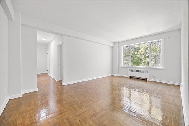 spare room featuring parquet floors and radiator