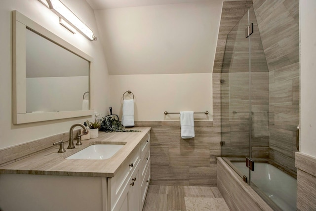 bathroom with vanity, lofted ceiling, and bath / shower combo with glass door