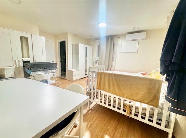 bedroom featuring a wall mounted AC and light hardwood / wood-style floors