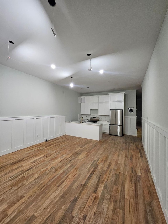 kitchen with hardwood / wood-style floors, white cabinets, sink, kitchen peninsula, and stainless steel appliances