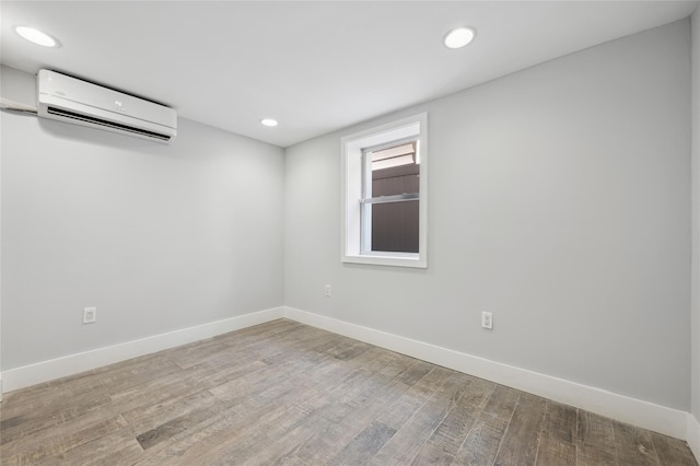 spare room featuring an AC wall unit and light hardwood / wood-style floors