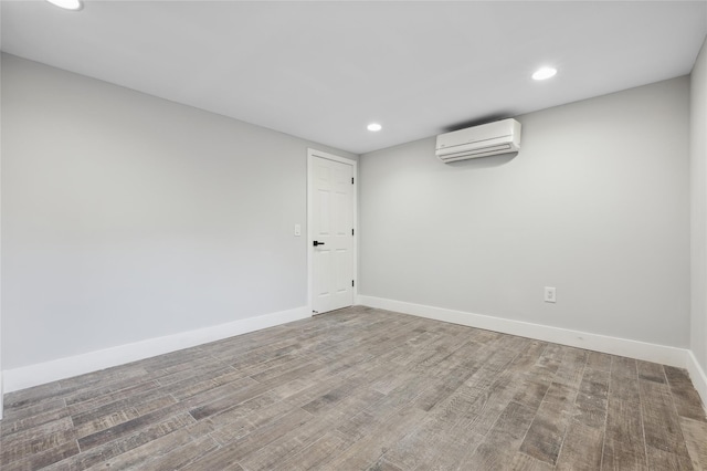 spare room featuring a wall mounted air conditioner and hardwood / wood-style floors